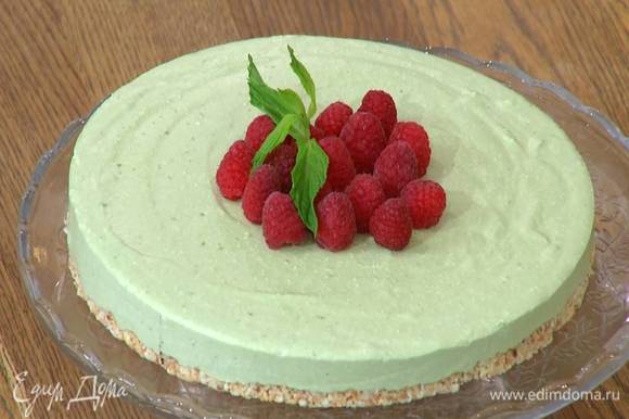 O cheesecake gelado é removido do molde, decorado com framboesas e folhas de hortelã.