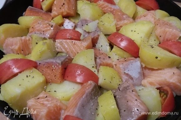 Картофель и лосося сложить в форму, в которой они будут запекаться. Между кусочками картофеля и лосося выложить половинки черри или дольки более крупных помидоров.